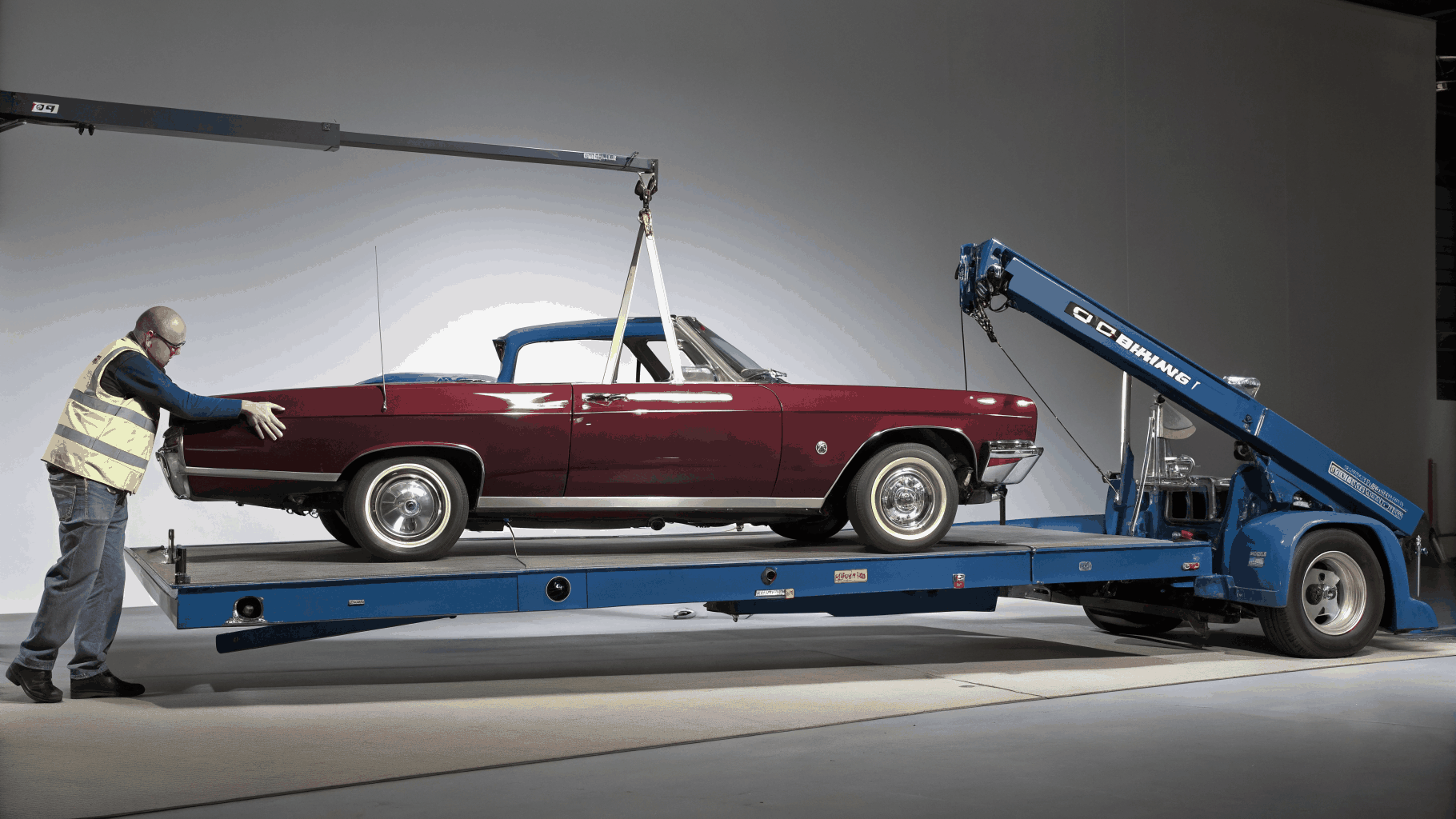 Hydraulic flatbed rollback tow truck securing passenger vehicle for damage-free transport